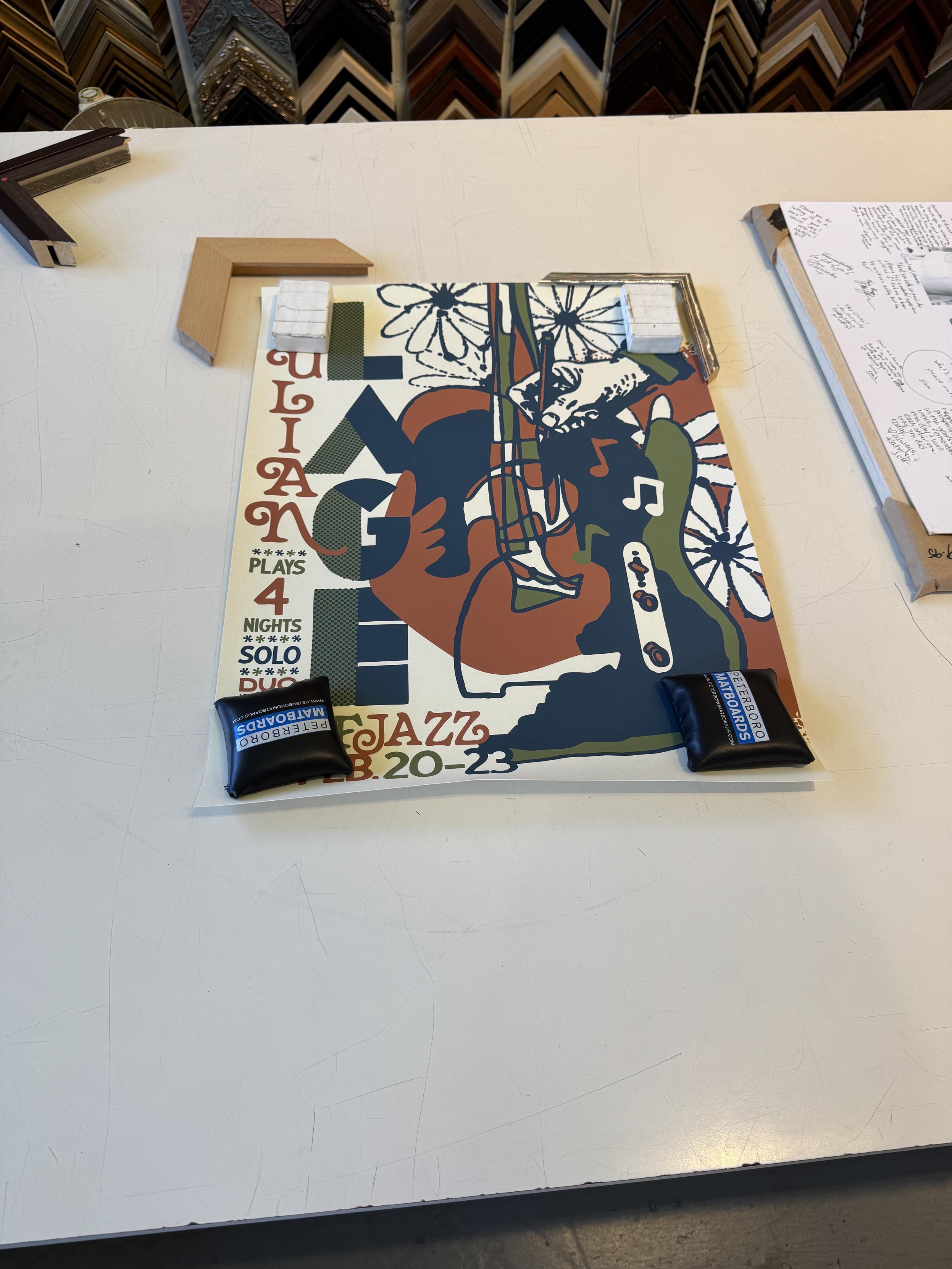 a normal sized (18x24”) poster for Julian Lage’s SF Jazz residence in dark blue, dark green, and maroon over cream featuring an abstract guitar, a telecaster control set, flowers, and a hand holding a pen for some reason.I was trying to decide between the closest wood I could get to an acoustic guitar, and a metal that in hindsight looks a lot like fret wire. the metal was 1/3rd the cost of the wood, so I went w/ the metal."Julian” is horizontal in a script font on the left in red and LAGE is in all block sans in blue and green. the bottom left corner lists the dates and says:plays 4 nightssoloduo????