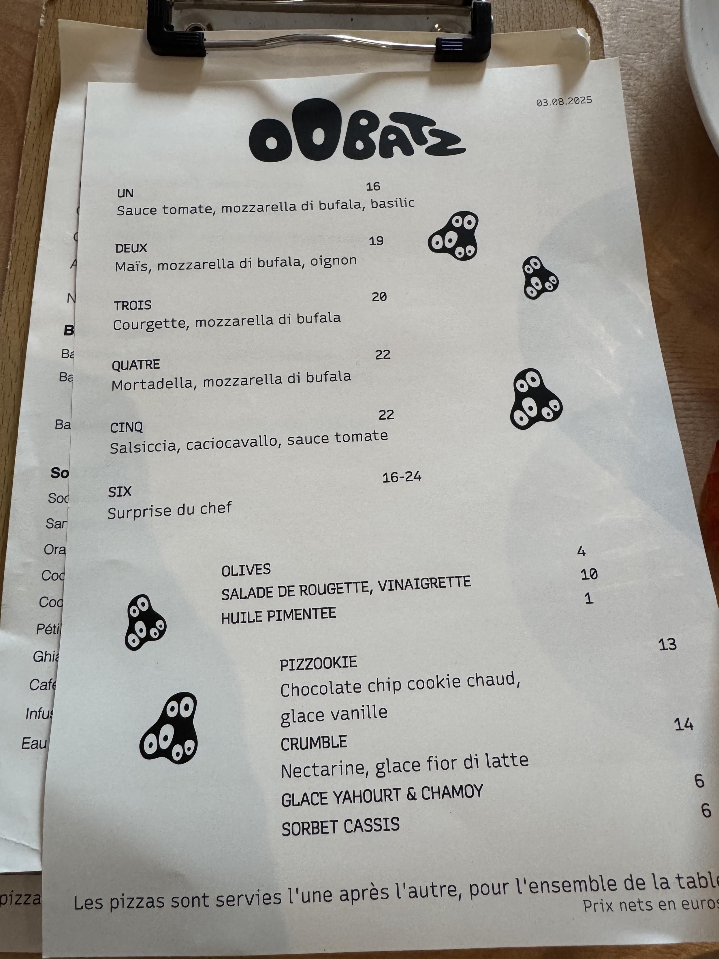 a phone camera pic of the menu at Oobatz, we got the deux, trois, sinc, and sixOobatz16UNSauce tomate, mozzarella di bufala, basilic19DEUXMaïs, mozzarella di bufala, oignon20TROISCourgette, mozzarella di bufala22QUATREMortadella, mozzarella di bufala22CINQSalsiccia, caciocavallo, sauce tomate16-24SIXSurprise du chef03.08.2025Les pizzas sont servies l'une après l'autre, pour l'ensemble de la tablPrix nets en euro