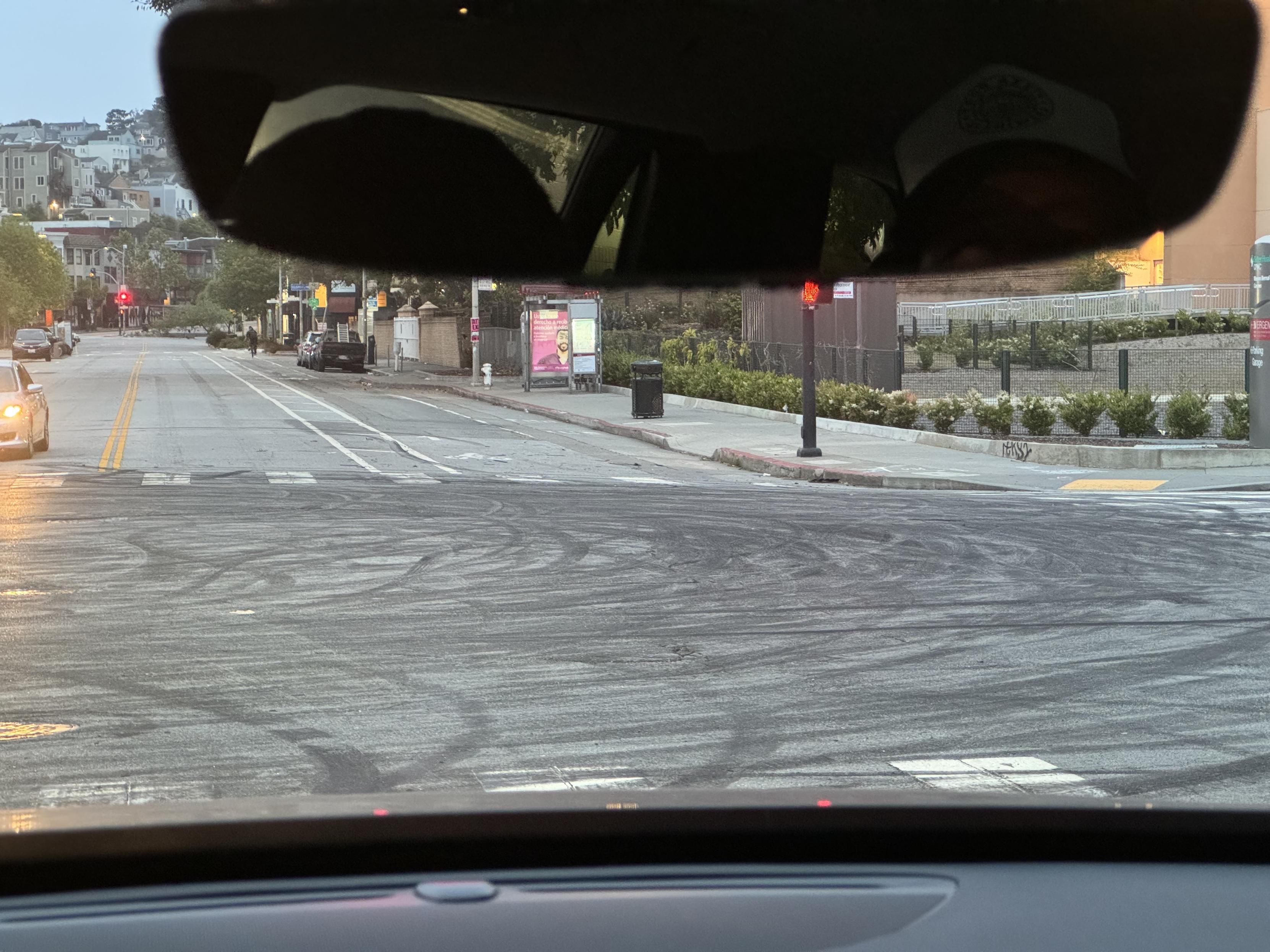 photo of an intersection covered in tire rubber left by cars and motorcycles doing donuts, taken from my cab on the way to the airport