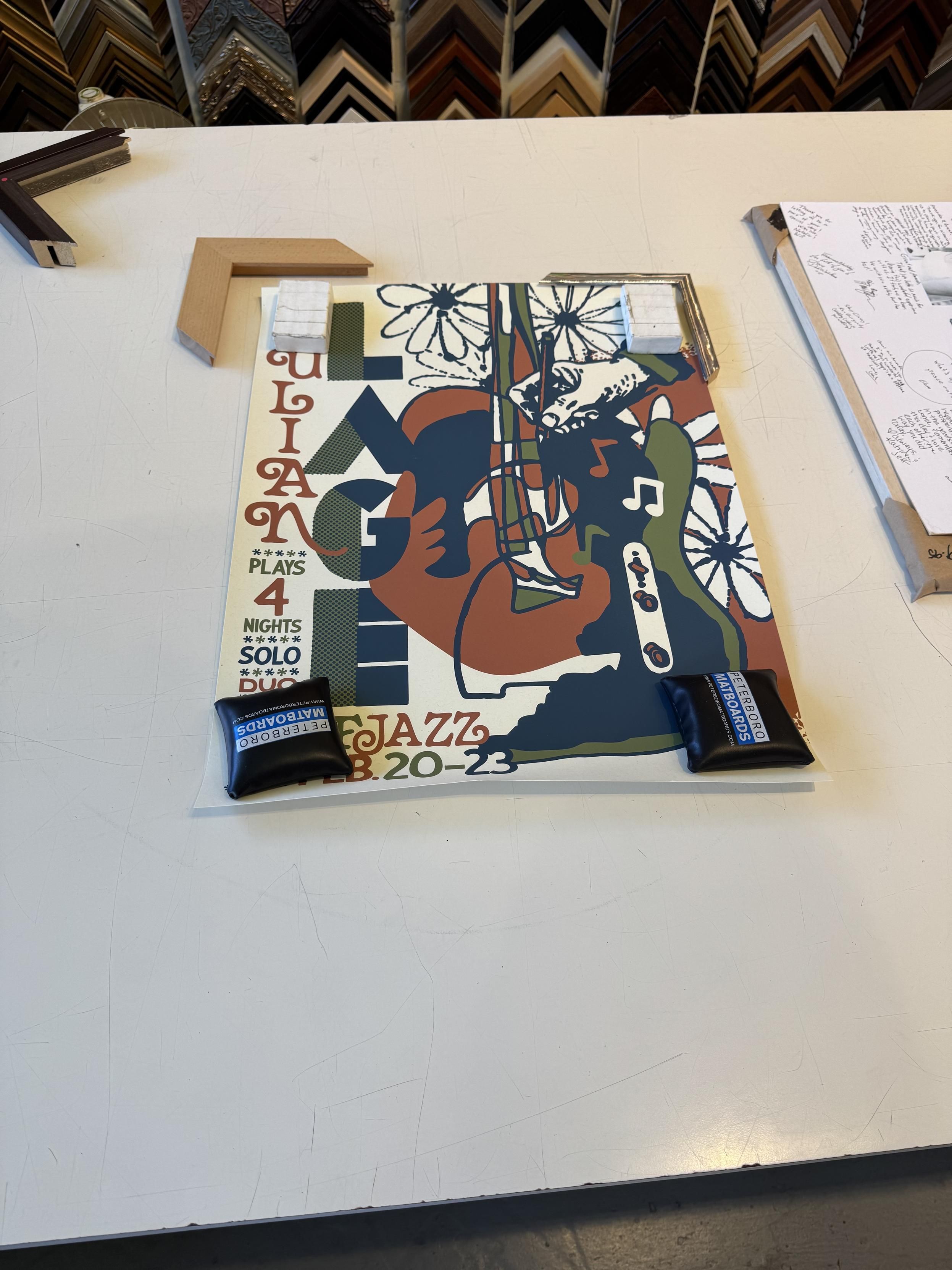 a normal sized (18x24”) poster for Julian Lage’s SF Jazz residence in dark blue, dark green, and maroon over cream featuring an abstract guitar, a telecaster control set, flowers, and a hand holding a pen for some reason.I was trying to decide between the closest wood I could get to an acoustic guitar, and a metal that in hindsight looks a lot like fret wire. the metal was 1/3rd the cost of the wood, so I went w/ the metal."Julian” is horizontal in a script font on the left in red and LAGE is in all block sans in blue and green. the bottom left corner lists the dates and says:plays 4 nightssoloduo????