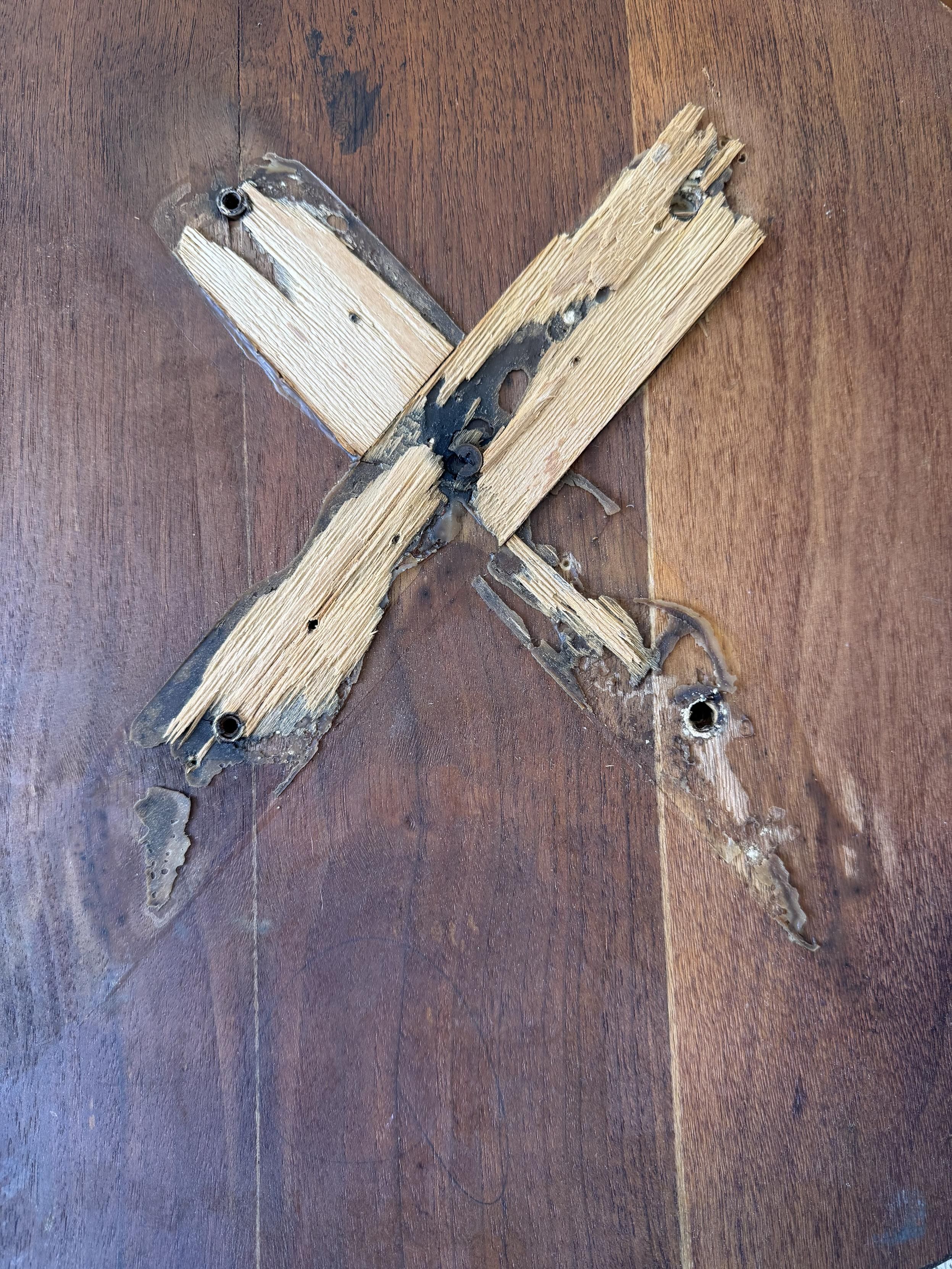 the ruins of the base, wood from the veneer still glued in places, screw hardware remains in three, the top right corner is stripped completely.